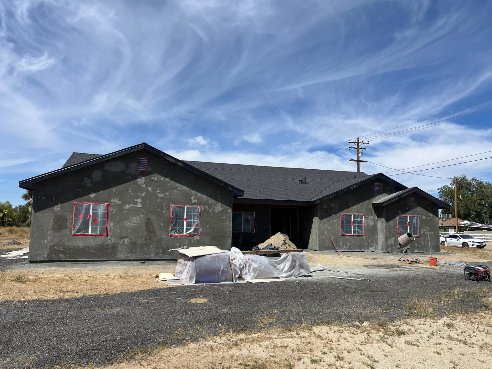 Single-story investment property mid-renovation with fresh stucco and taped windows